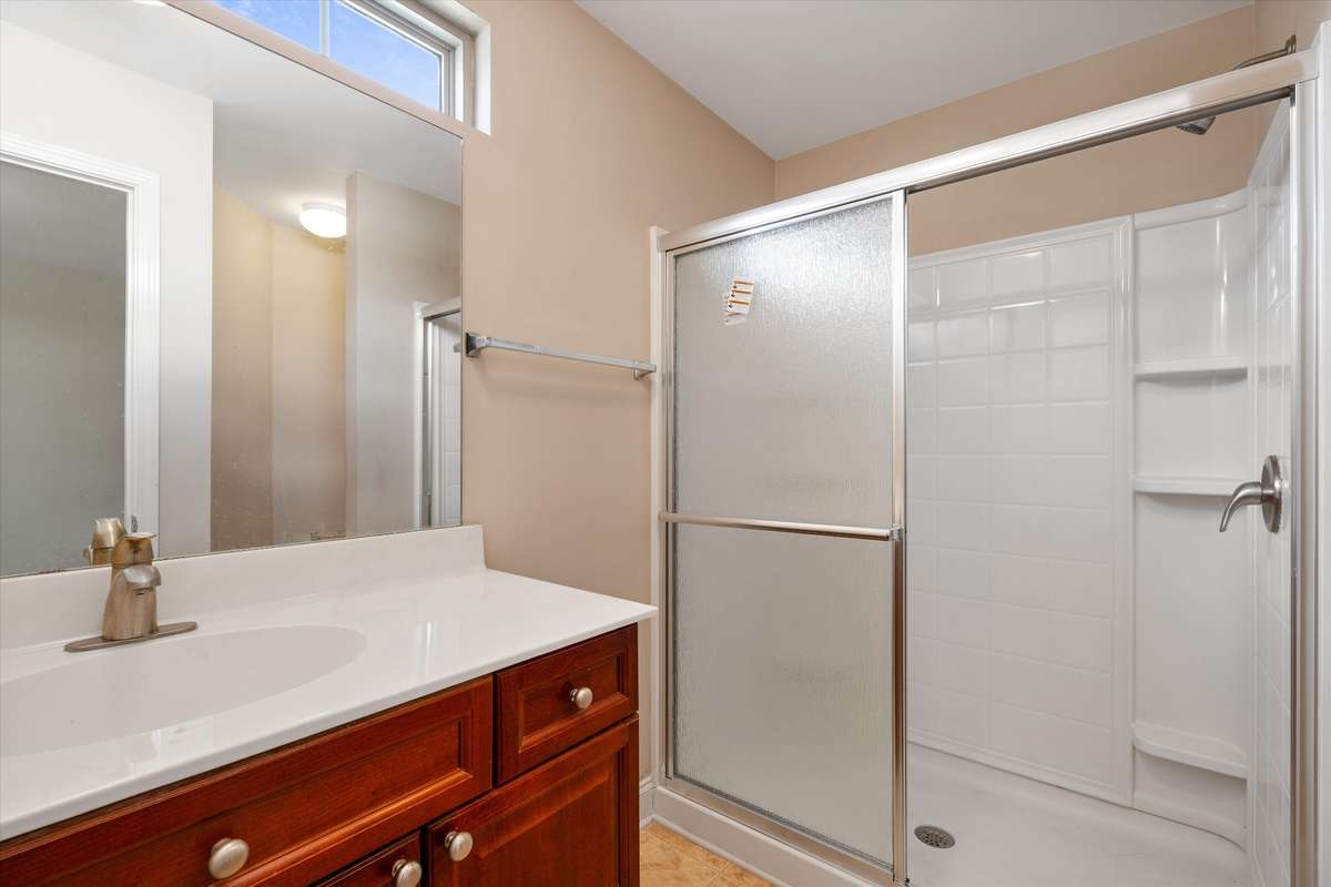 Clean and functional en-suite bath featuring a walk-in shower and ample vanity space 