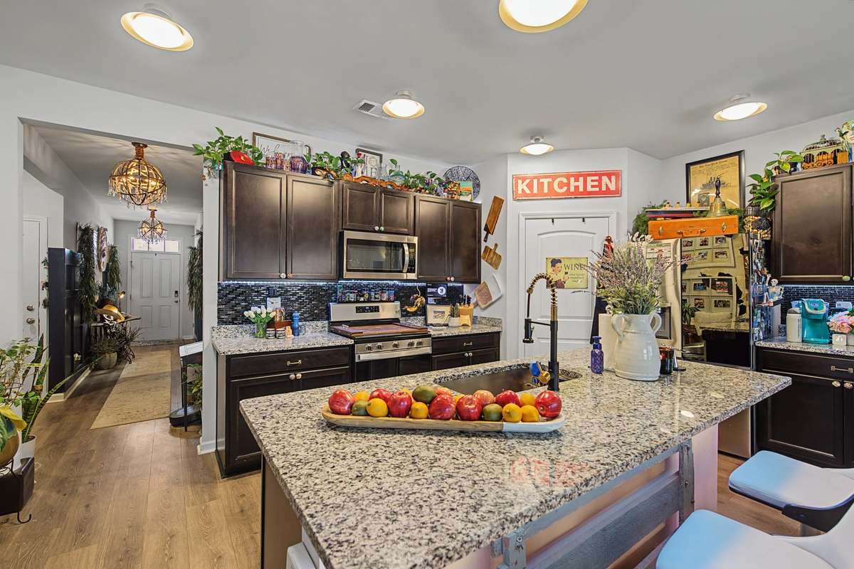 Kitchen (Wide View): Modern chef's kitchen featuring sleek dark cabinetry, granite countertops, and stainless steel appliances