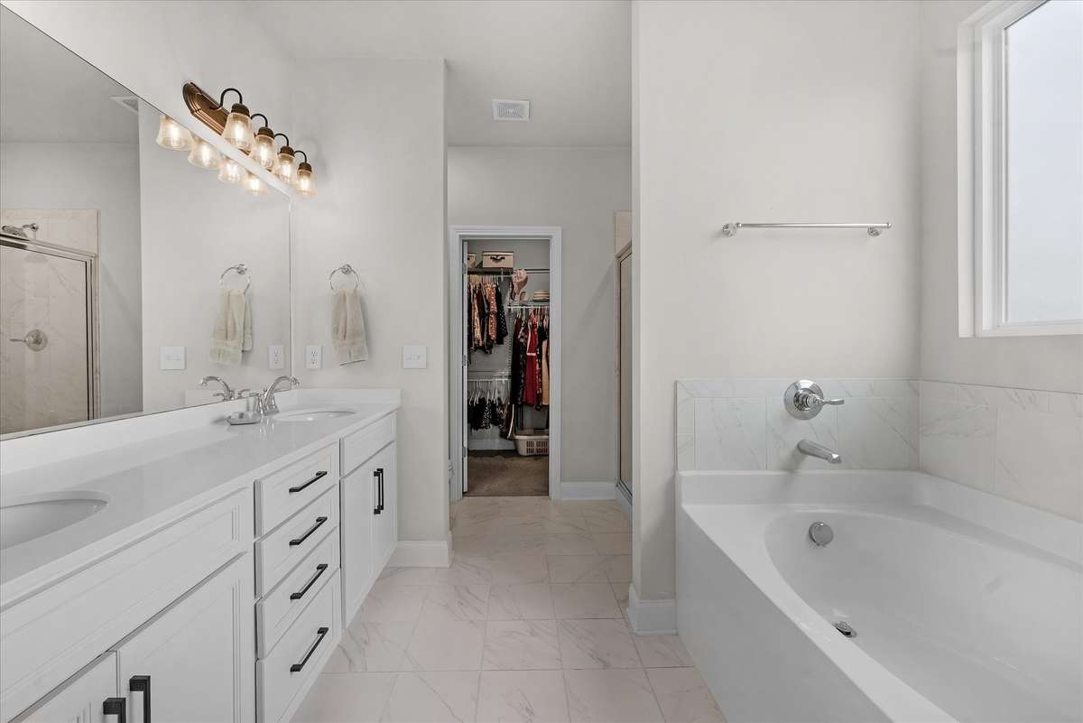 The primary suite bath with dual sinks, notice the drawer stack, the generously sized soaking tub walk-in closet.