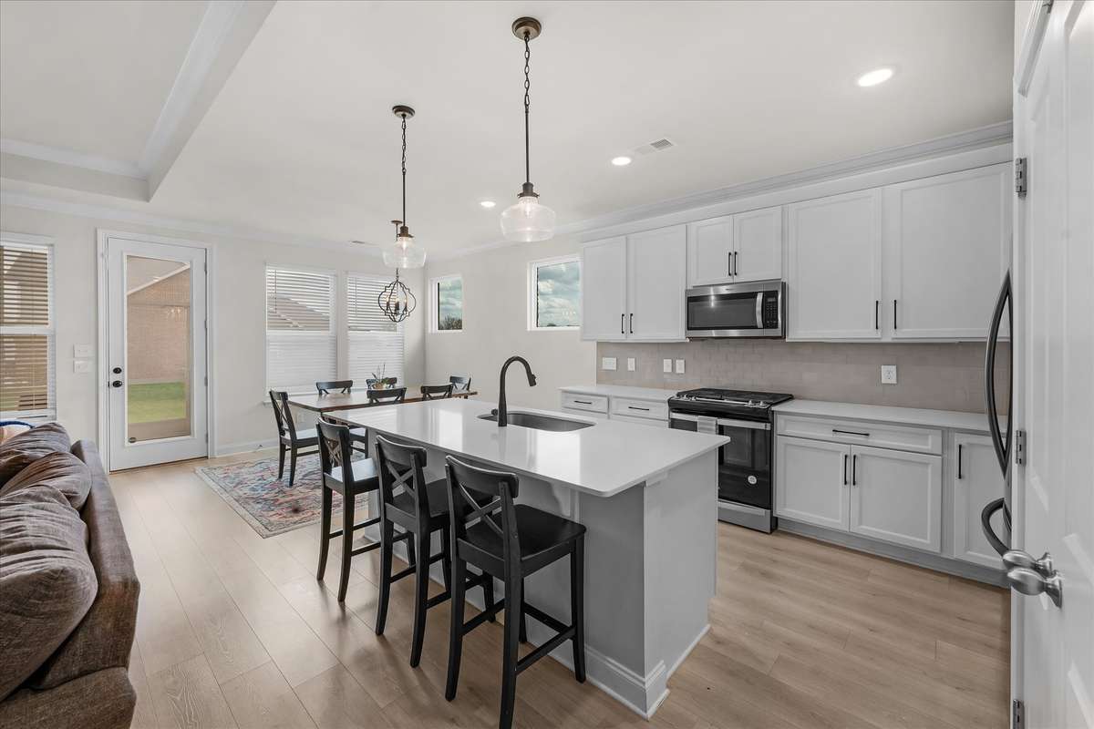 Quartz countertops, backsplash, white cabinets, and undercounter lighting checks all the kitchen boxes.
