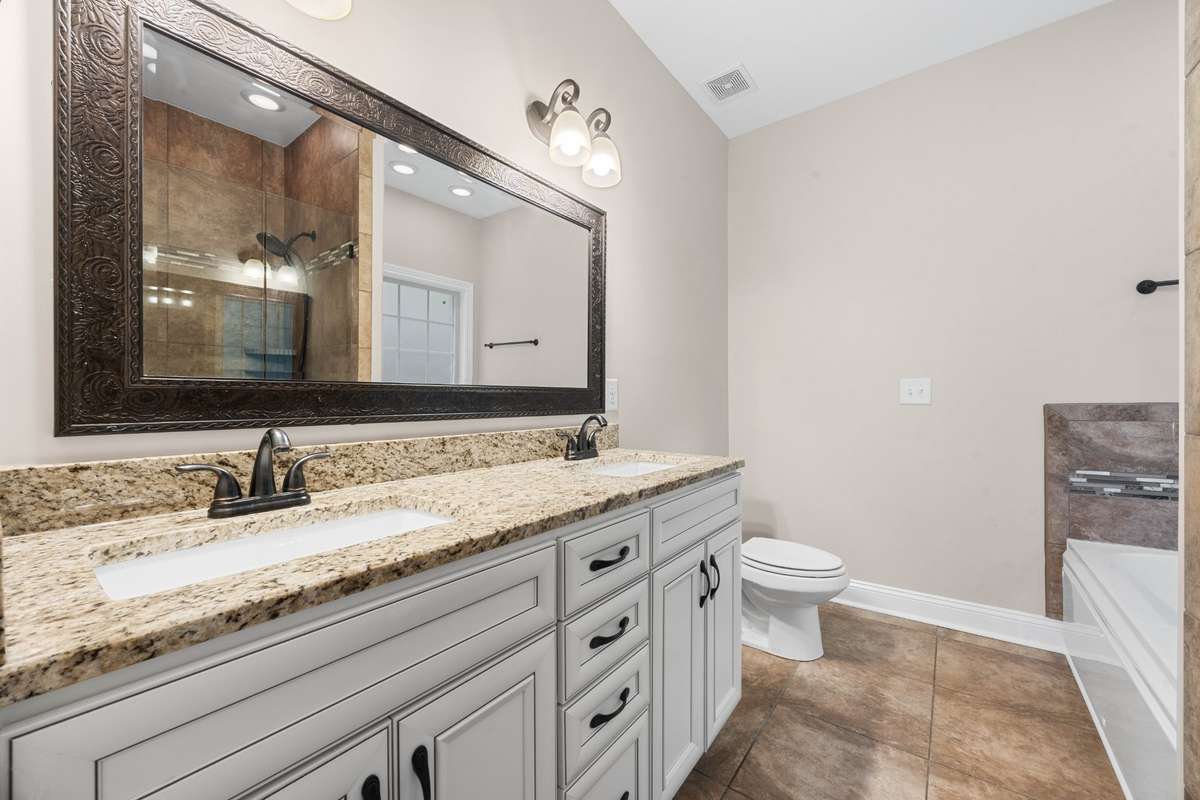 full bath with double vanity sink, granite countertops in the bedroom on the main level