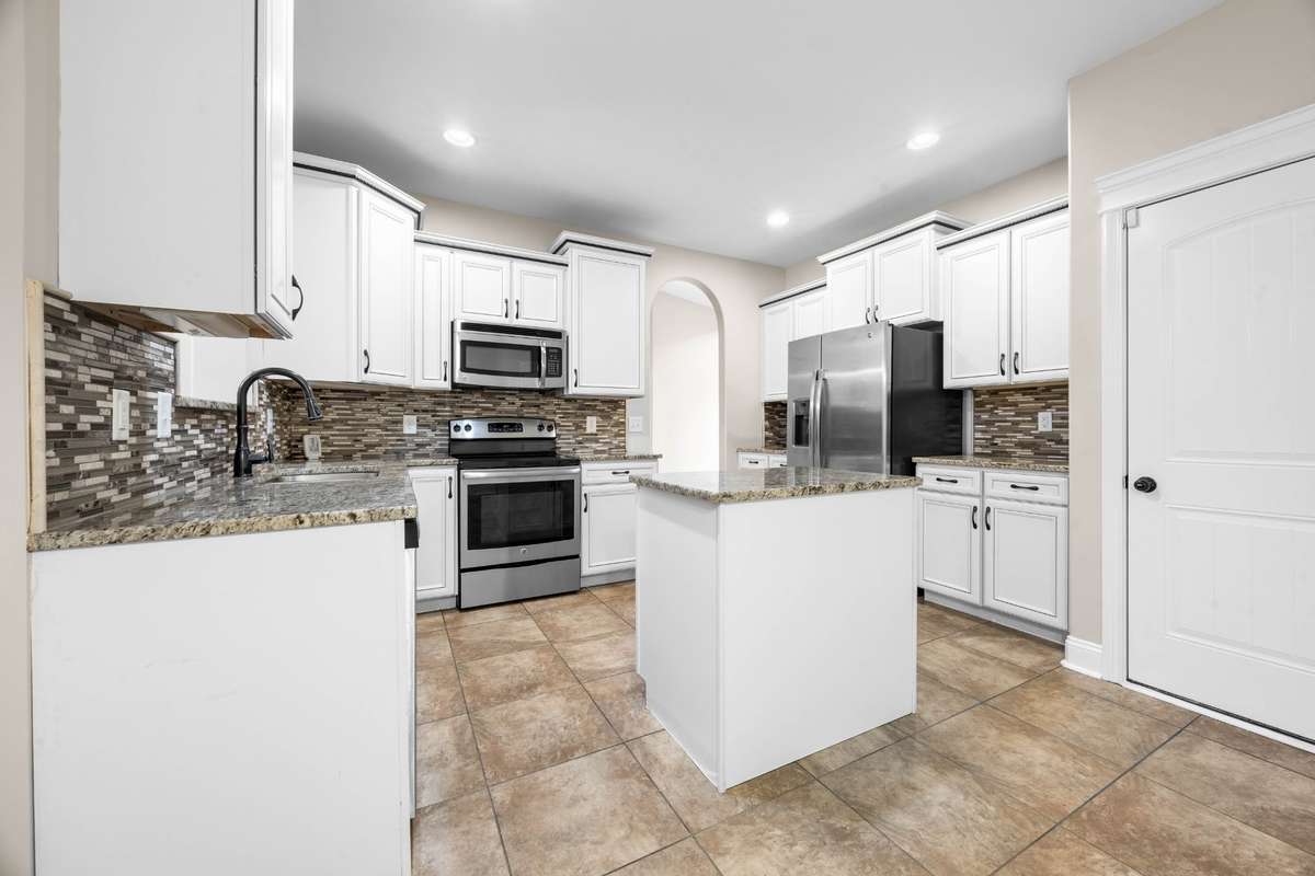 stainless steel appliances in the kitchen, granite countertops, tile floors
