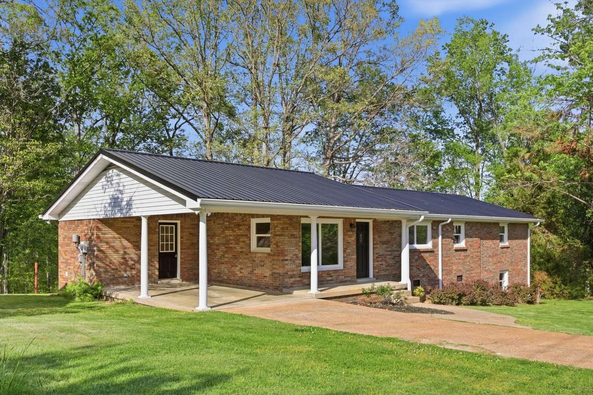 Attached carport on main level with entrance to kitchen. Concrete driveway and sidewalk. Covered front porch