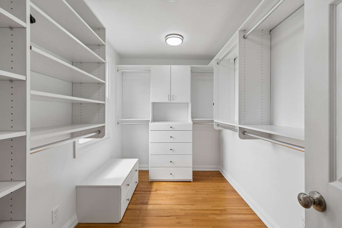 Primary closet with so many builtins and seat to put on shoes