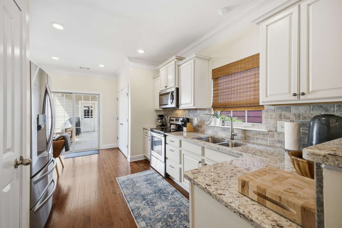 The kitchen boasts a stylish stone backsplash and upgraded soft-close cabinetry and drawers, flowing seamlessly into the living and dining areas for a perfect open-concept layout.