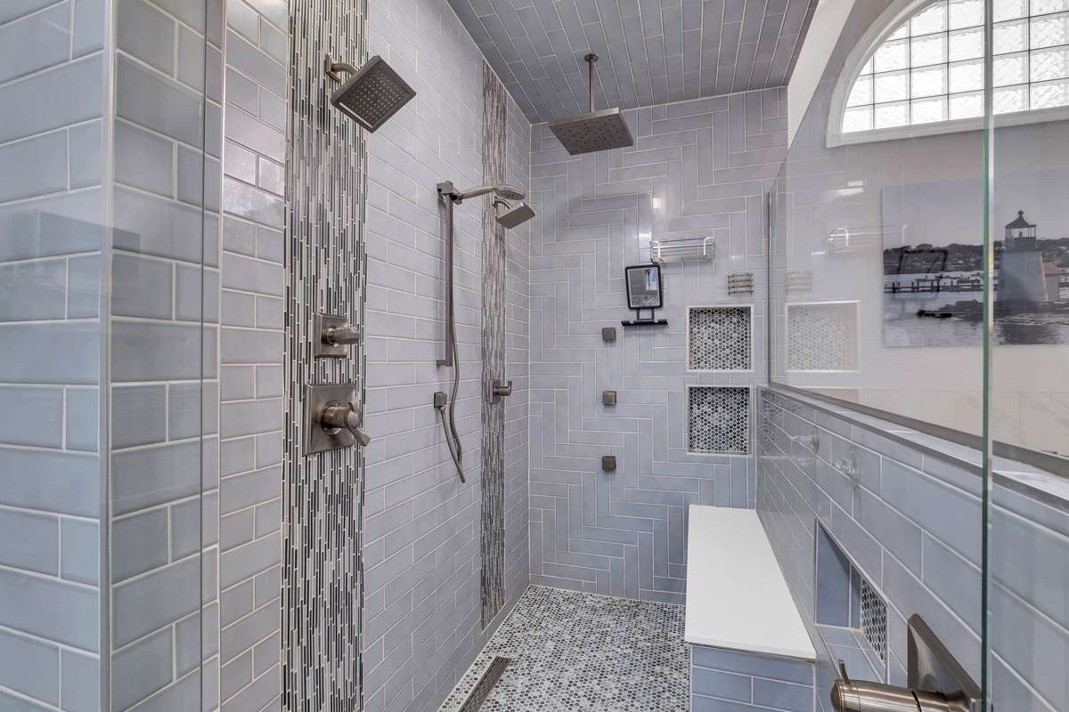 The shower is equipped with dual heads, a rainfall feature and a built-in bench creates a high-end spa experience while offering significant practical benefits for storage and accessibility