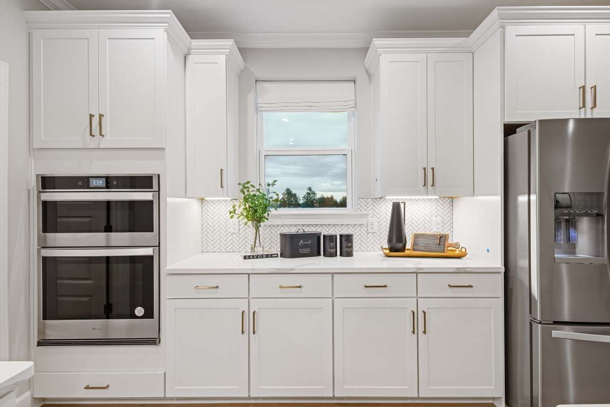 Stunning gourmet kitchen includes built in wall oven/microwave/hood vent, cabinets to the ceiling, quartz countertops, ceramic tile backsplash!