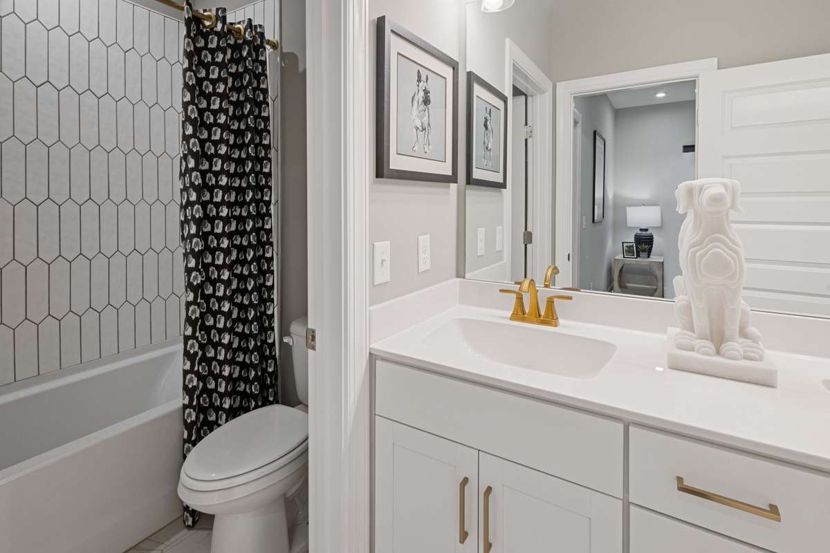 Full bathroom off of the loft upstairs features double vanity with quartz countertops, ceramic tile floor, and tub/shower combination.