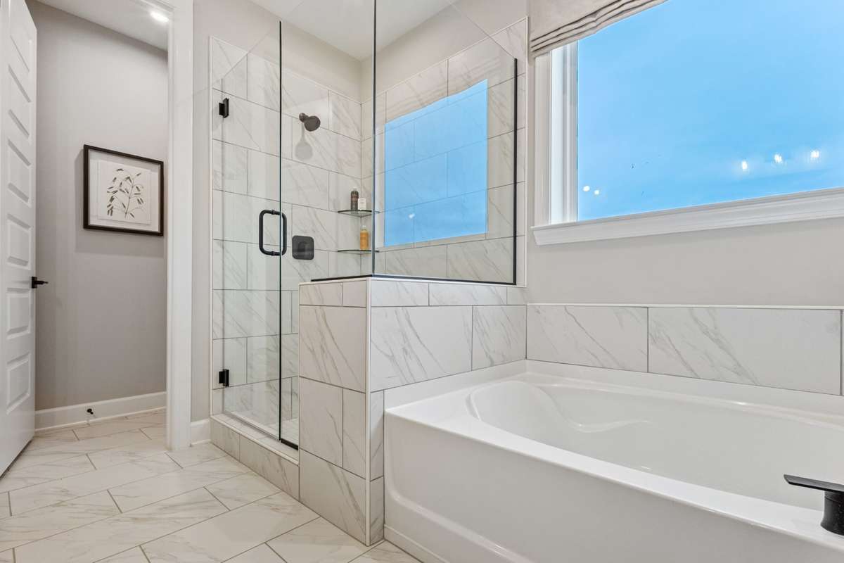 Live in luxury in your primary suite bathroom featuring double vanities, quartz counters, ceramic tile floors and shower wall, and tons of storage space!