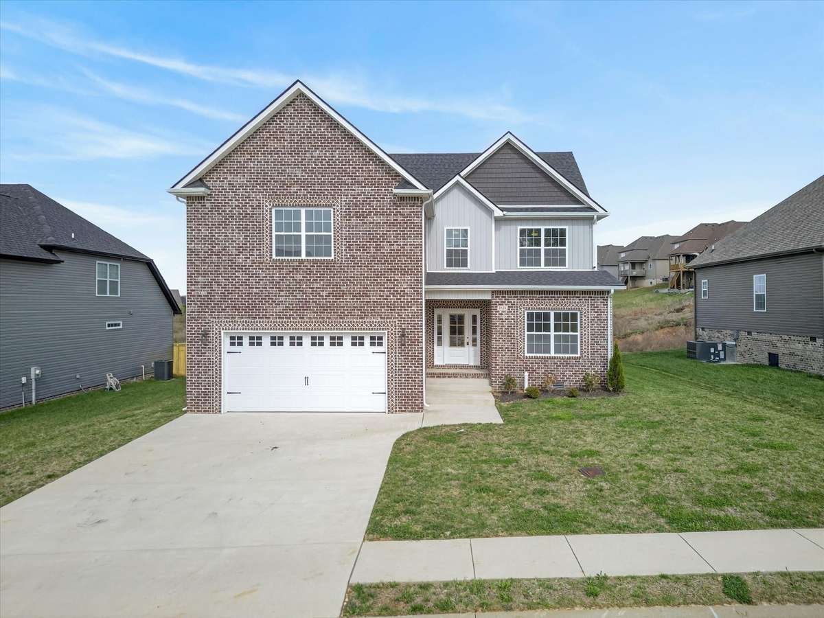 Charming front exterior with brick detail and attached garage.