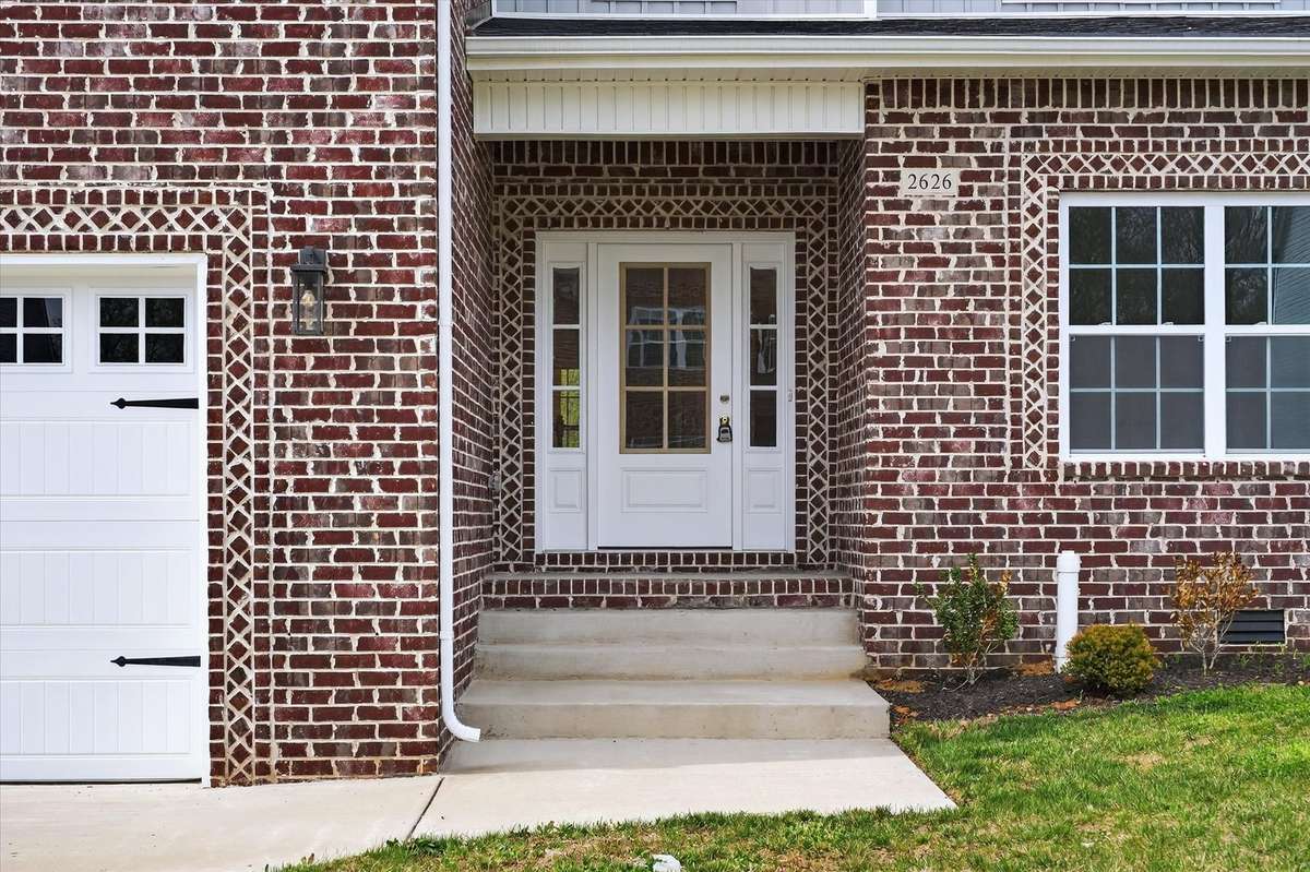 Inviting covered front entry with classic brick detail and welcoming porch