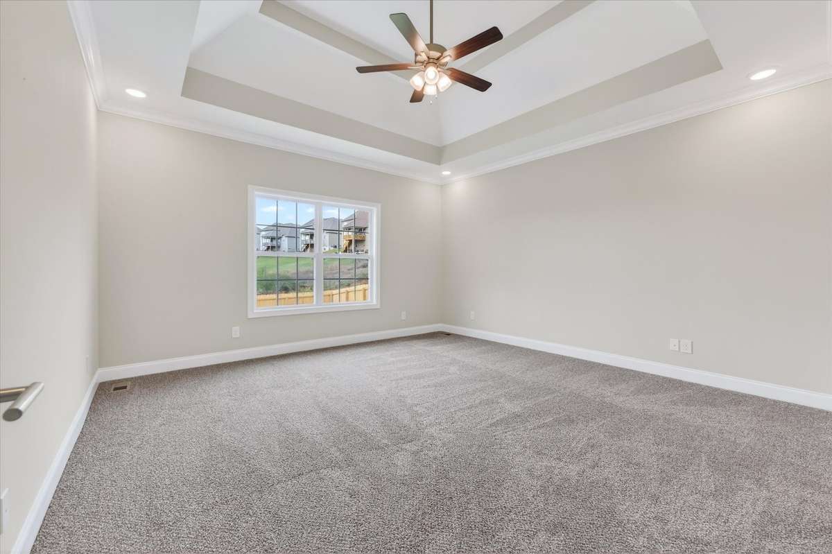 Large primary suite featuring tray ceiling and natural light