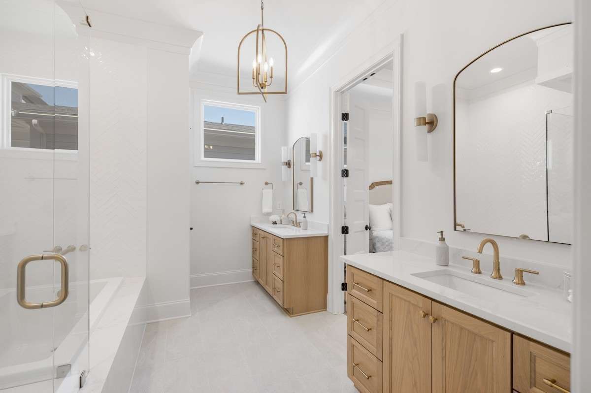Primary Bathroom Suite with beautiful woodwork, dual vanities, framed mirrors, and champagne bronze fixtures.