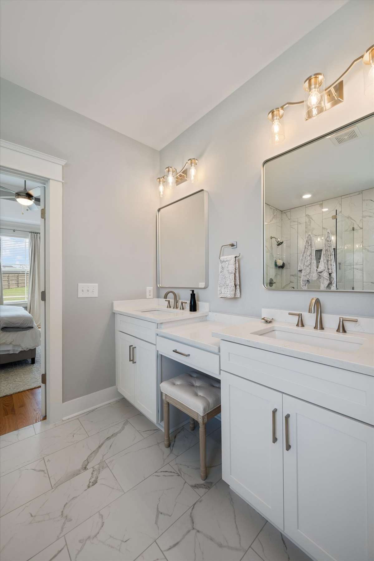 Primary bathroom with double vanities and a sitting area for makeup.