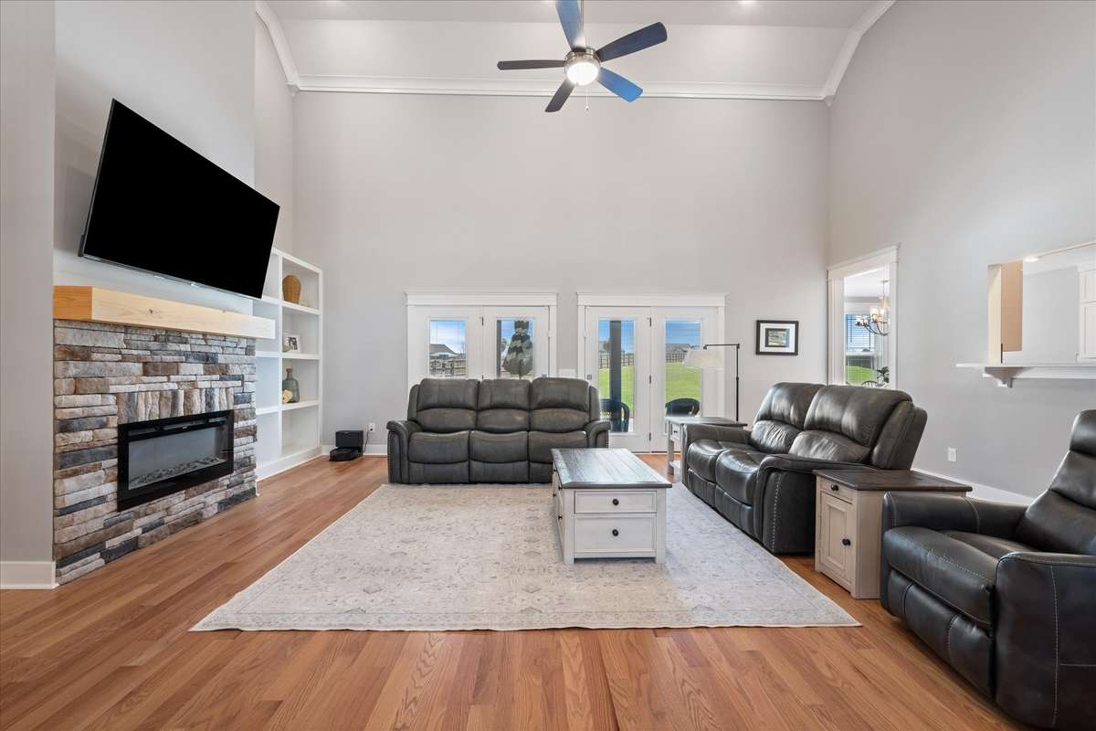 Expansive living room with fireplace and built in display shelves on either side.