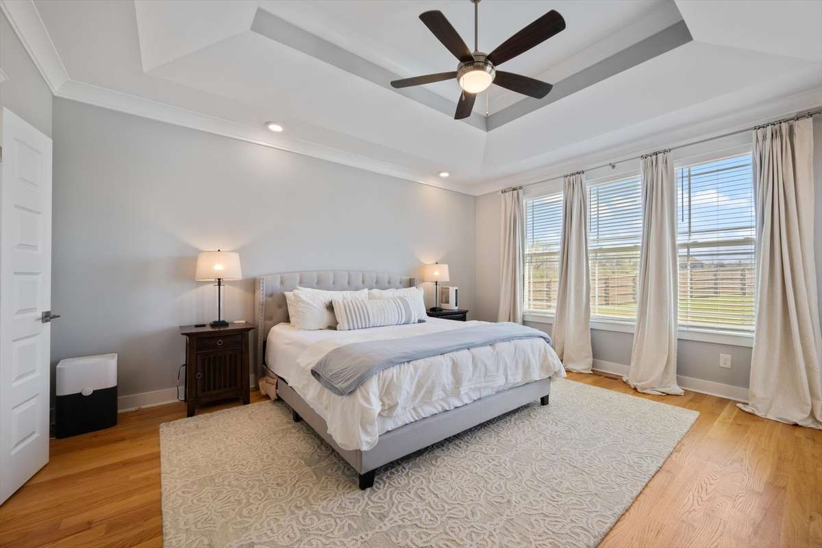 Primary bedroom with plenty of natural light through the tall windows.