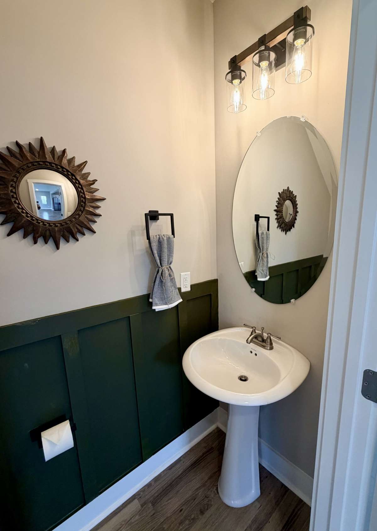 Simple and sleek, the decorator light, frameless mirror, and pedestal sink feel well appointed. Good to know: This half bath has a black towel ring, larger towel bar for guest towels, matching tissue holder, and hook on the back of the door.