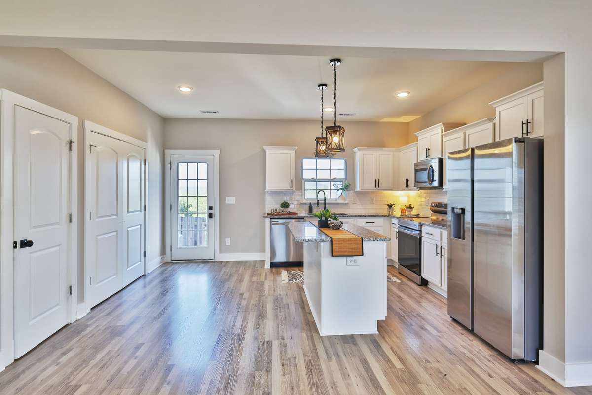 On the left side, you'll find a half bath, generous walk-in lighted pantry with wire shelves, and a utility room with included washer and dryer, shelves, water heater.