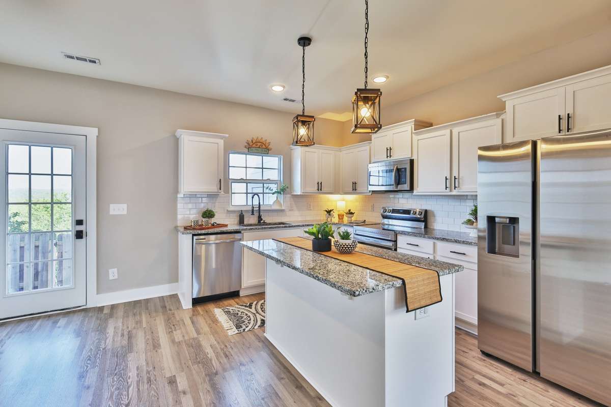 Granite counters in fully equipped kitchen features extra storage in the island with breakfast bar and outlets for appliances. Side by side fridge with ice and water in door, smooth top stove, microwave range hood, and dishwasher.