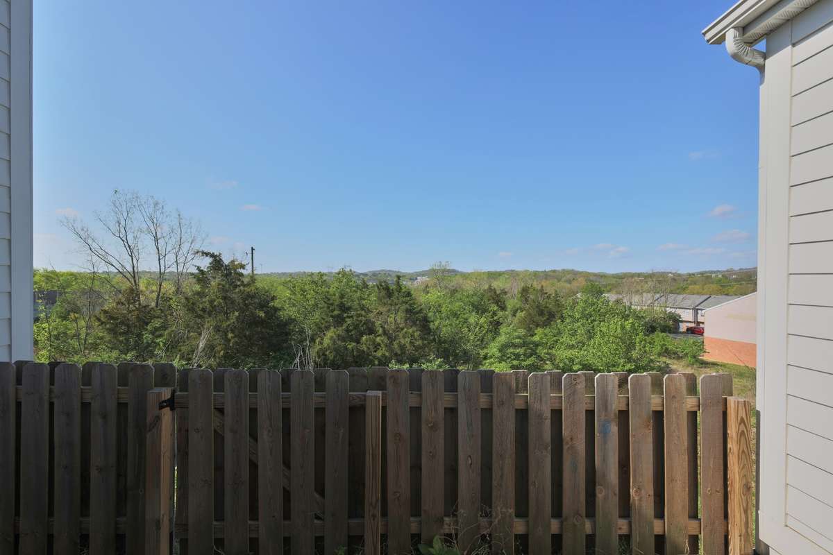 Outside, you'll find a concrete patio with a picket fence and a beautiful view.