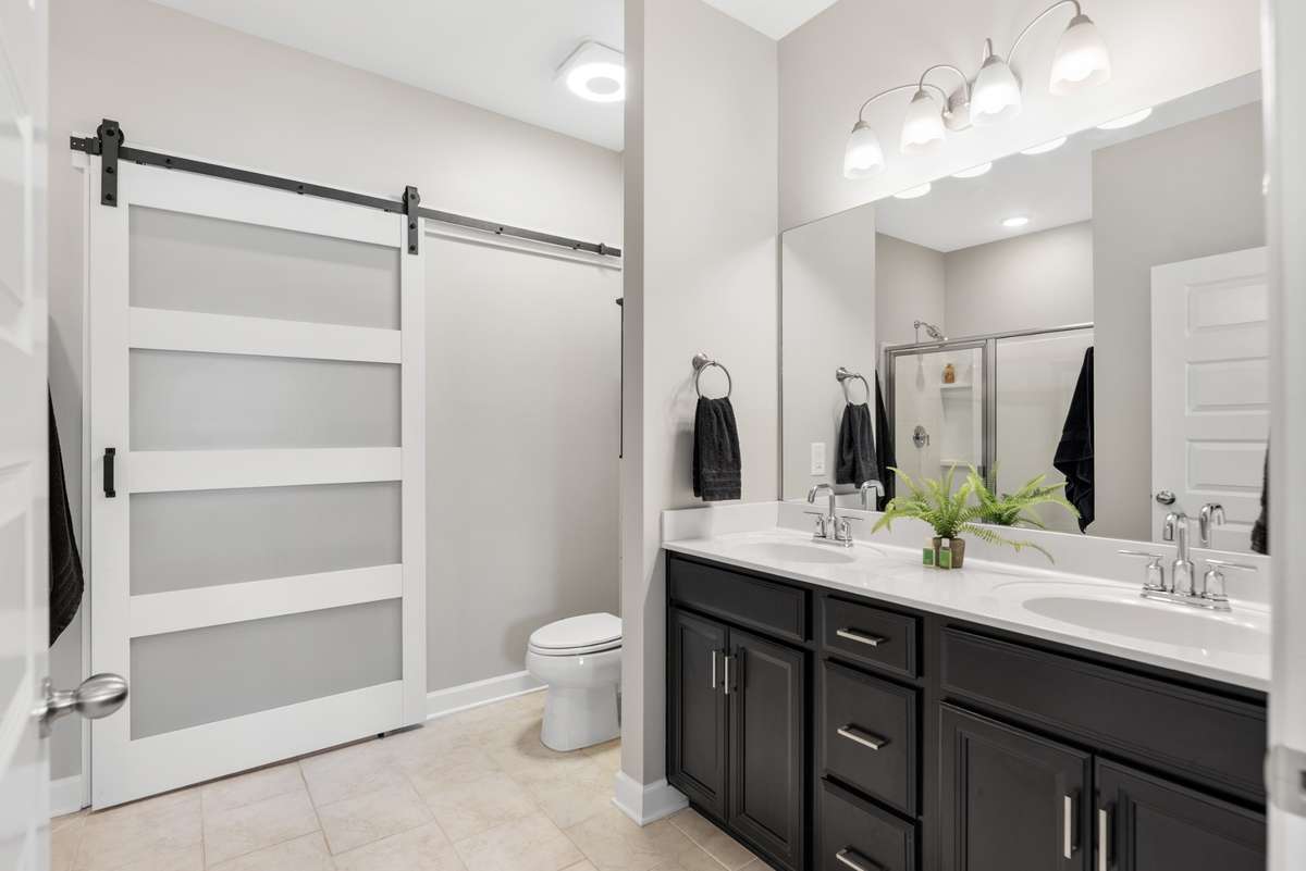The ensuite bathroom has double vanities, tile flooring and a sliding door to maximize your space.  Behind that door is yet another customized walk-in closet by Closets by Design.