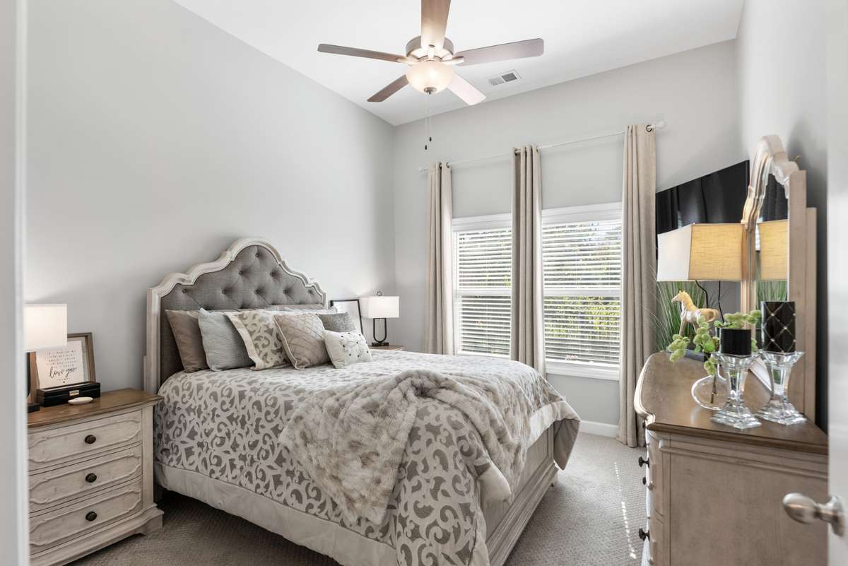 The primary suite is on the main floor - a benefit of the end unit.  Enjoy the view of the wooded area behind the home.  The drapes, hardware and blinds are already in place for you!