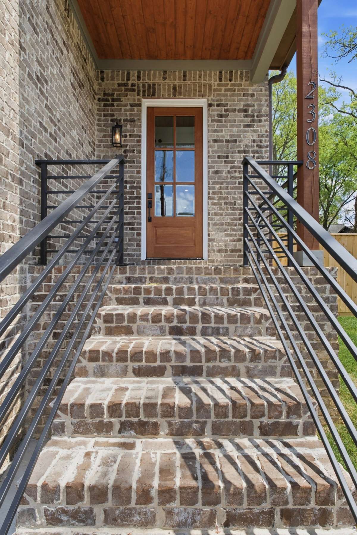 Brick steps, aluminum railing, and beadboard ceiling on the front porch