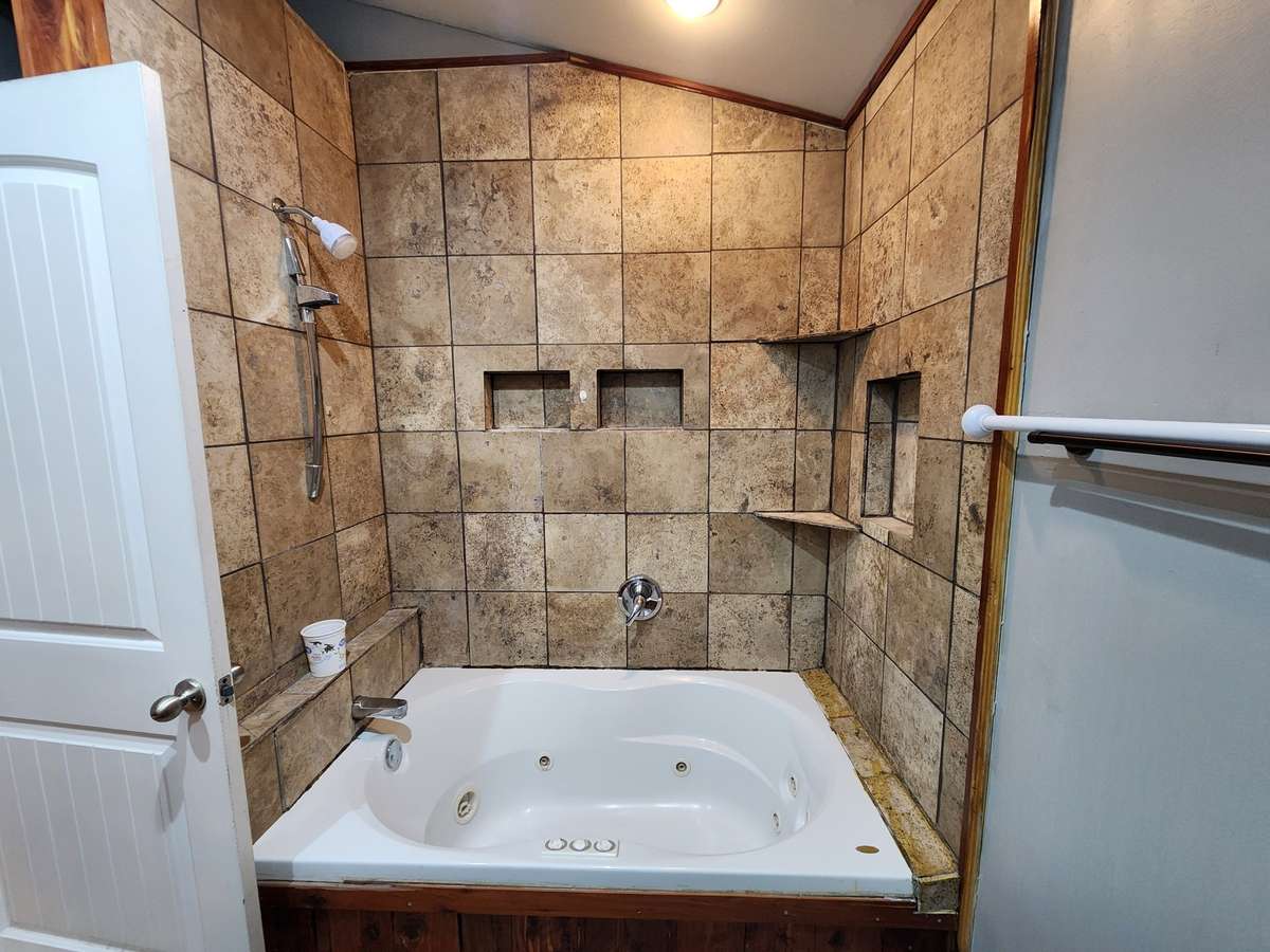 Primary Bath features Whirlpool Tub and Shower surrounded by Tile.