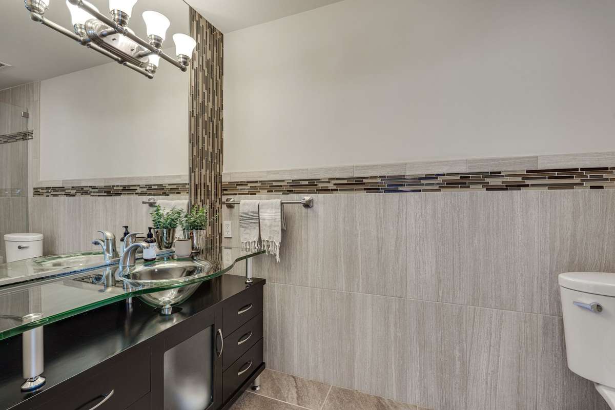 The ensuite primary bath has a custom vanity, updated lighting, wainscoting and plenty of storage