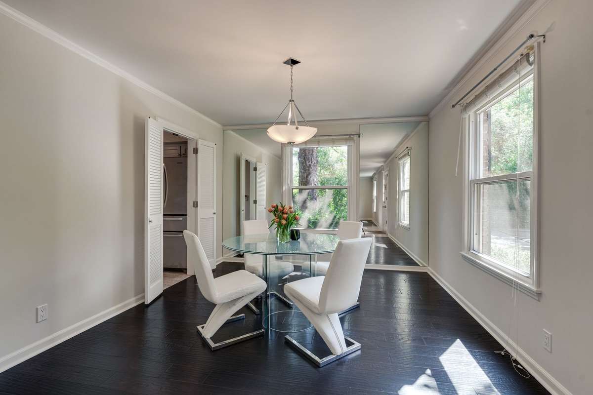 Dining room with 2 large windows that fill the space with natural light, enhanced by floor-to-ceiling mirrors that add depth and visual expansion