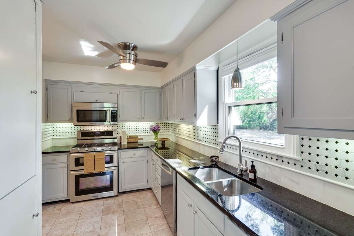 L-shaped kitchen featuring stainless steel appliances, a gas range, and a beautifully tiled backsplash, with a window above the sink that fills the space with natural light