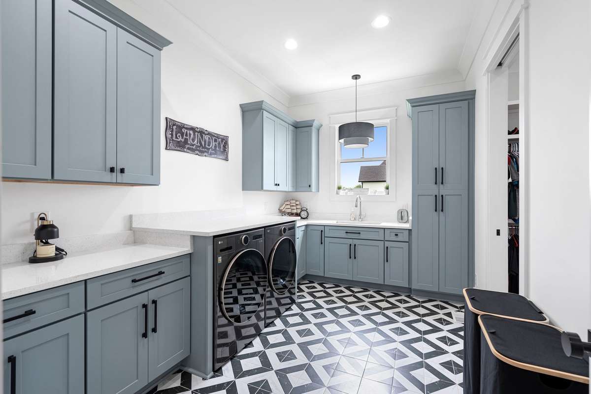 Large laundry room with custom cabinetry, sink, and designer tile flooring.