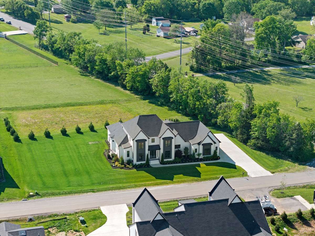 Stunning aerial view highlighting the home’s elegant architecture, manicured lawn, and expansive driveway.
