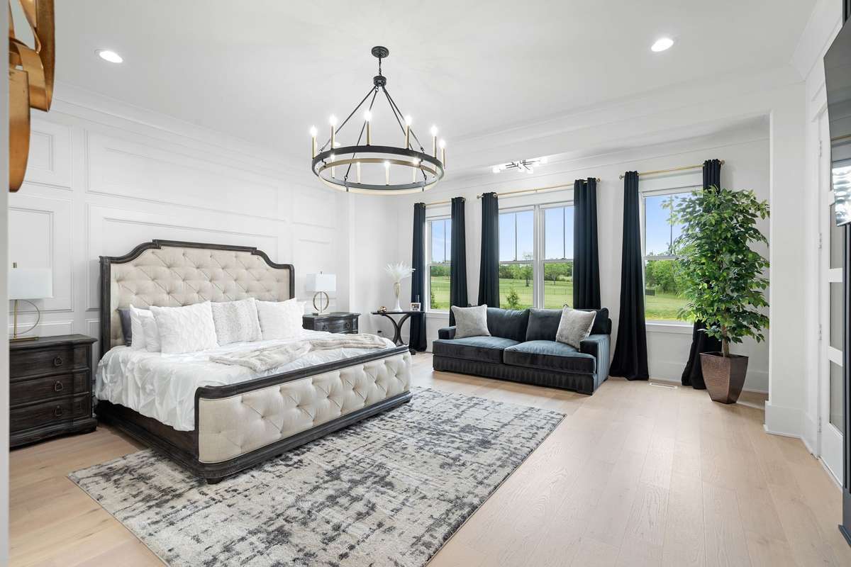Luxurious primary suite with expansive layout, sitting area, and serene backyard views.