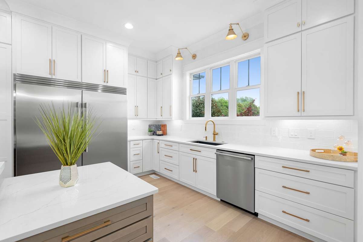 Light-filled kitchen with oversized windows, designer fixtures, and abundant cabinetry for storage.