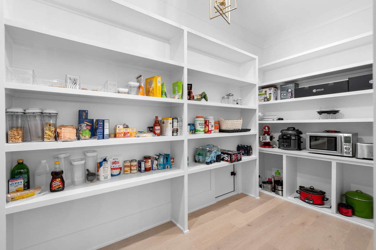 Expansive walk-in pantry with built-in shelving, ideal for storage, prep space, and small appliances.