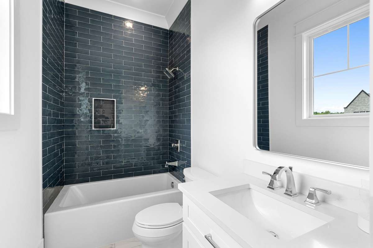 The stylish bathroom for Bedroom #4 features a sleek vanity, modern fixtures, and a striking tiled tub/shower combination.