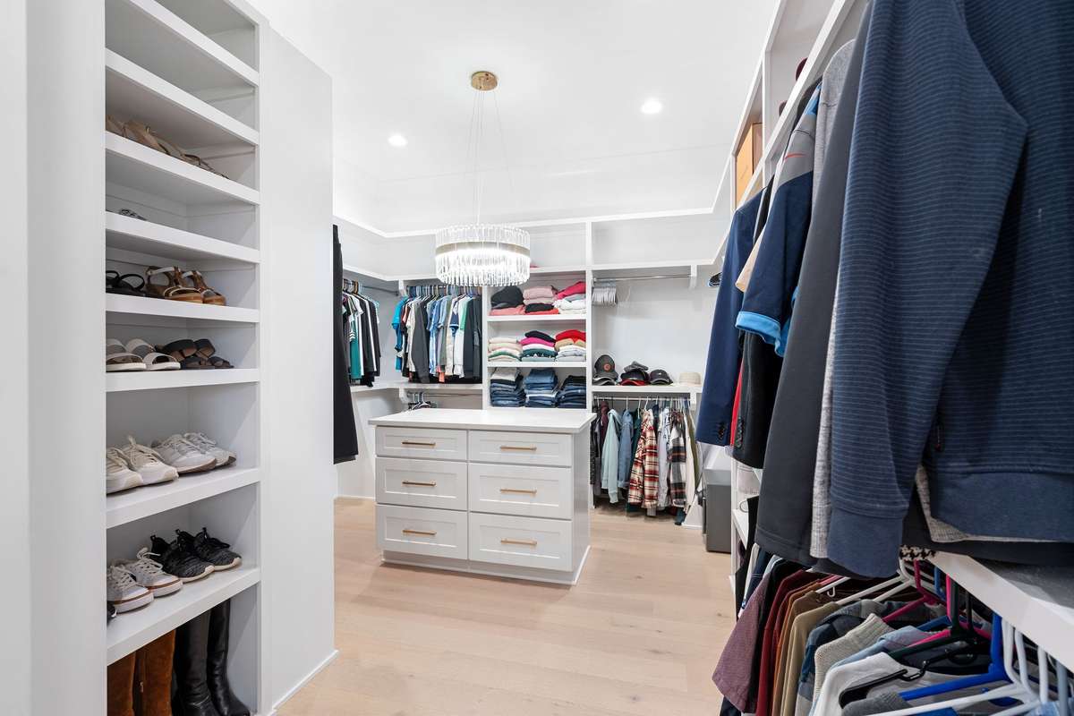 Spacious boutique-style closet with built-ins, center island, and designer lighting for ultimate organization.