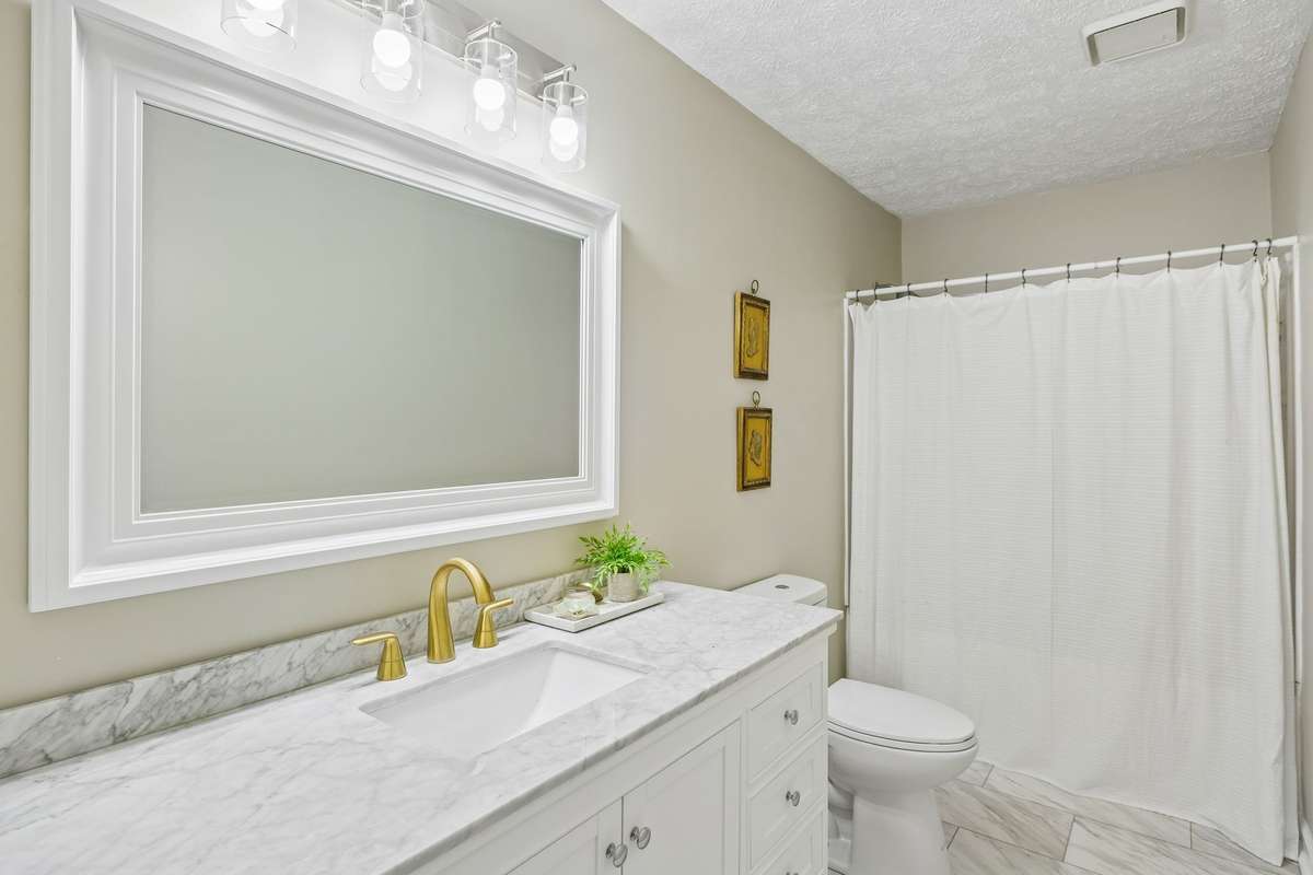 Fully renovated main full bath which is part of the owner's suite.  Quartz counters, beautiful fixtures and custom tile flooring.