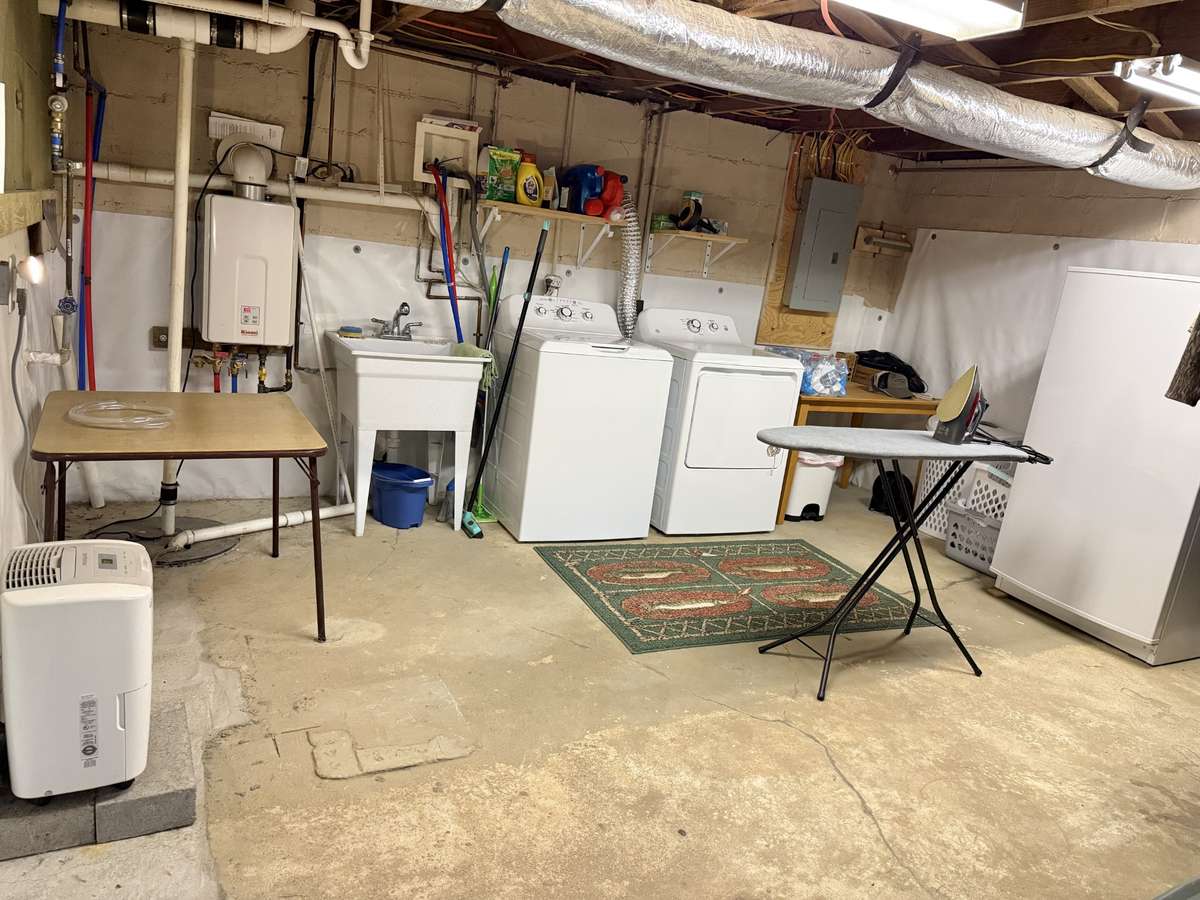 Usable Basement with tankless water heater, utility sink, and washer/dryer hookups