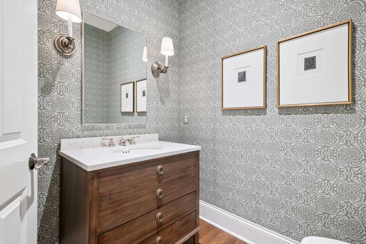 Lovely Powder Room with marble topped wooden vanity and designer wallpaper is centrally located off the main level living spaces.