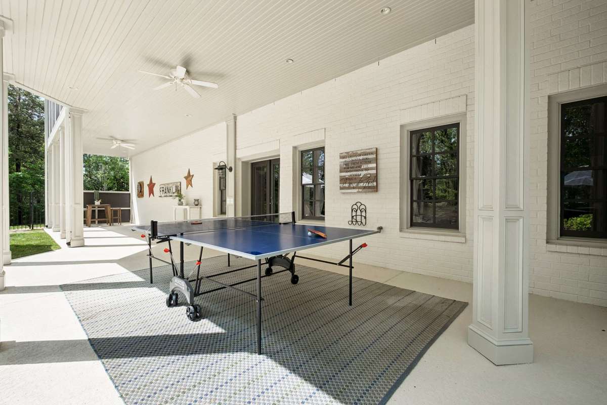 The covered porch off of the lower level provides another gathering area for playing, entertaining or relaxing in the shade by the pool.