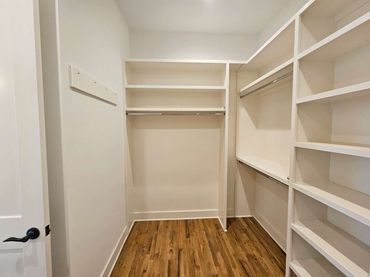 Another view of the primary closet with pull out rods for clothes staging or drying delicates.