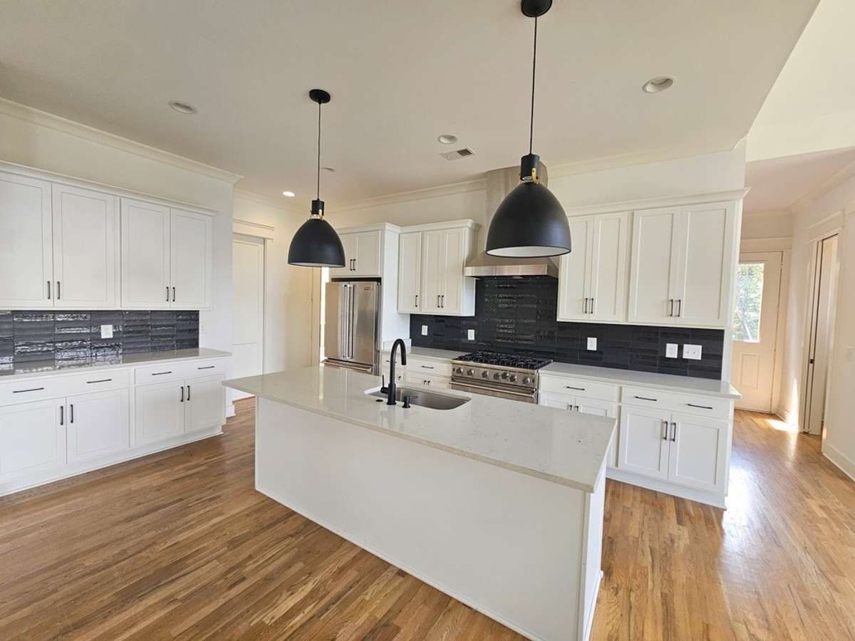 This view of the kitchen shows the serving counter with additonal drawers and cabinet space. To the left of the fridge is a butler's pantry and walk-in pantry.
