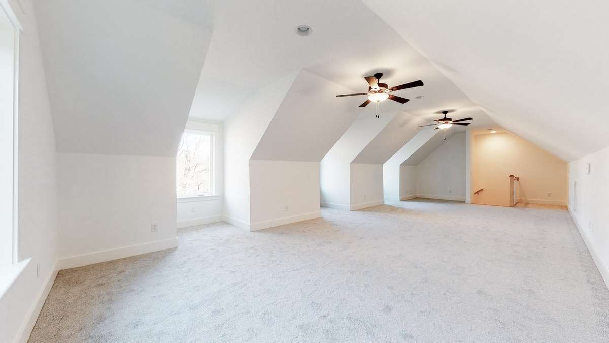 Another view of the bonus room with steps leading down to the entry hall by the half bath, laundry and main level garage entrance.