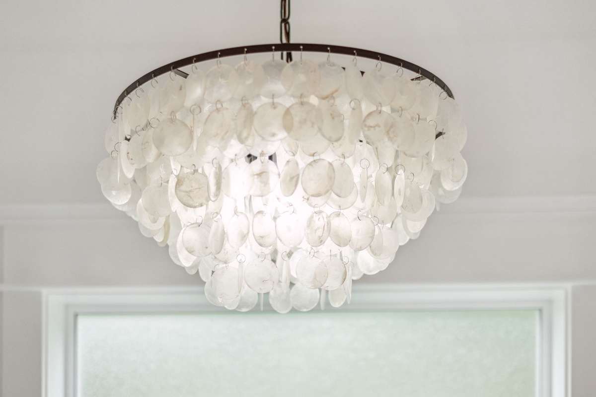 Wellmet Natural Capiz Shell Chandelier with a Coastal vibe is located above the soaking tub in the primary bathroom suite.