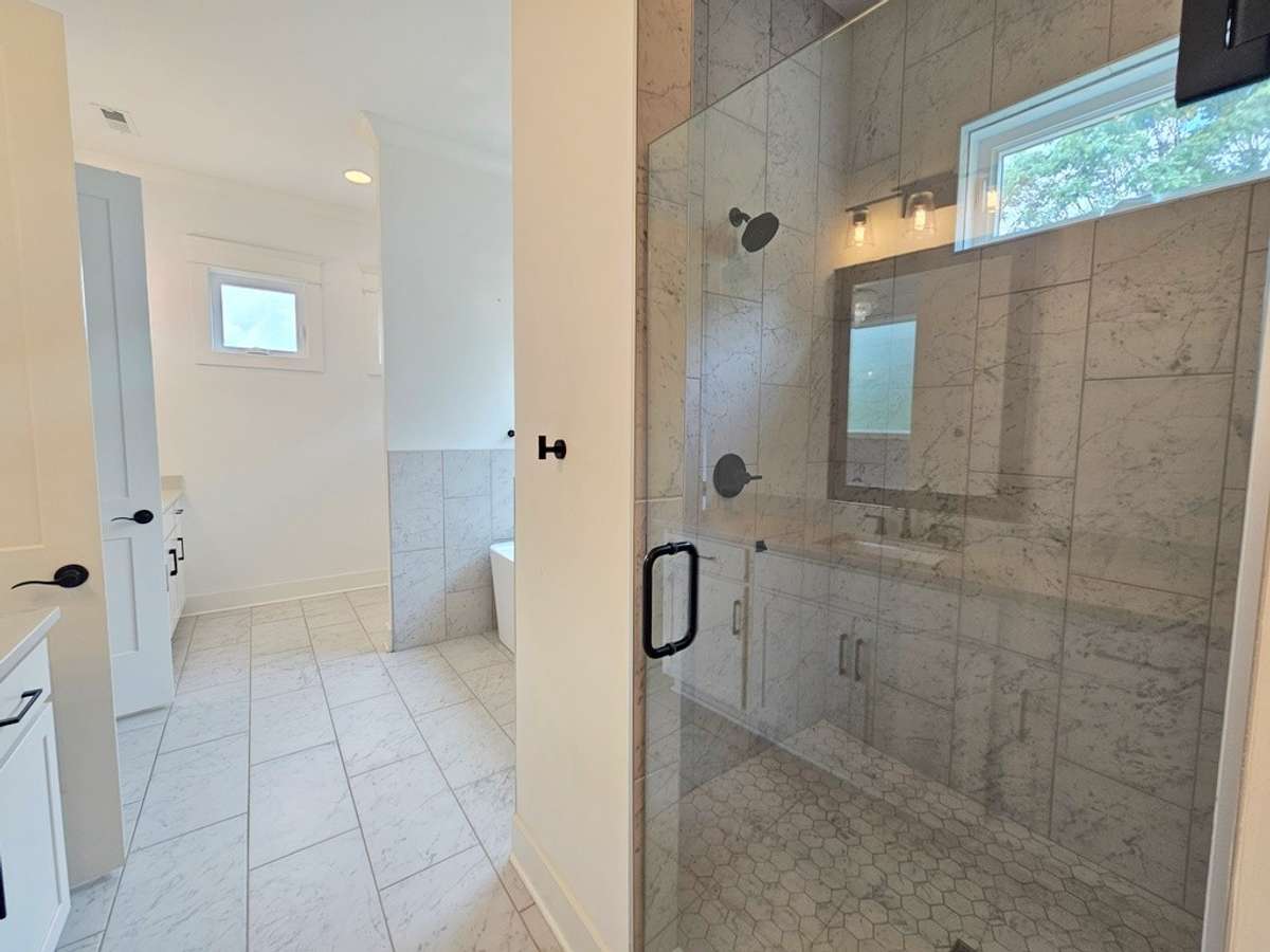 Separate walk-in tiled shower with glass door and bench.