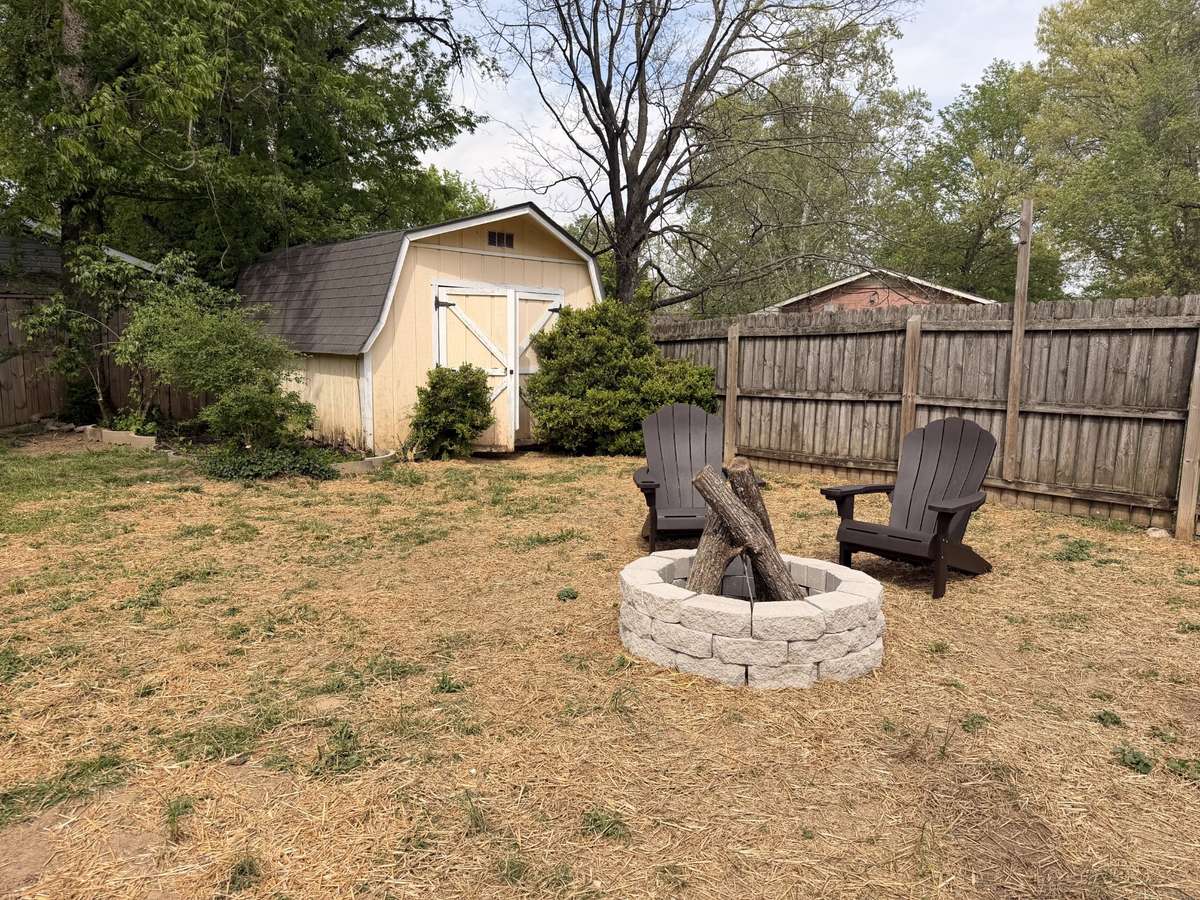 Large backyard with fire pit area and spacious storage shed.