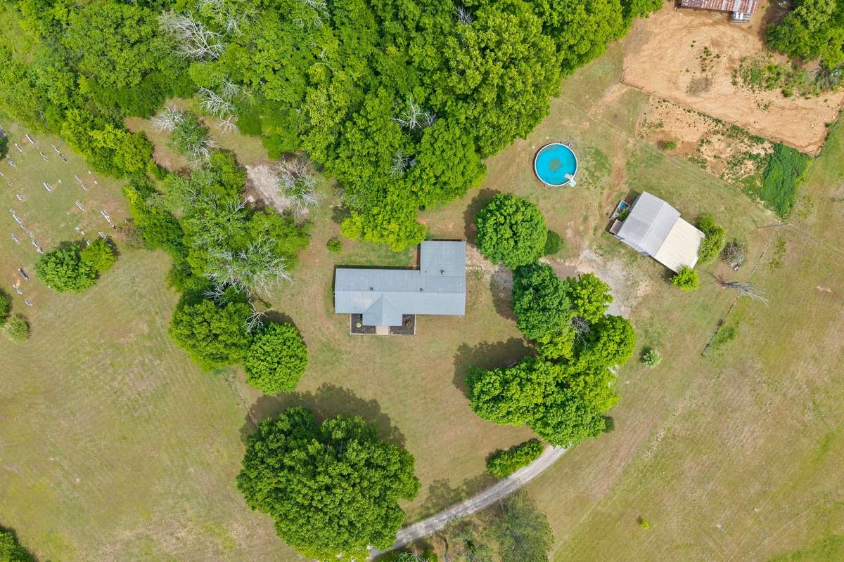 Private tree lined yard with stables and stalls, chicken coop, pool, barn, storage building and RV pad.
