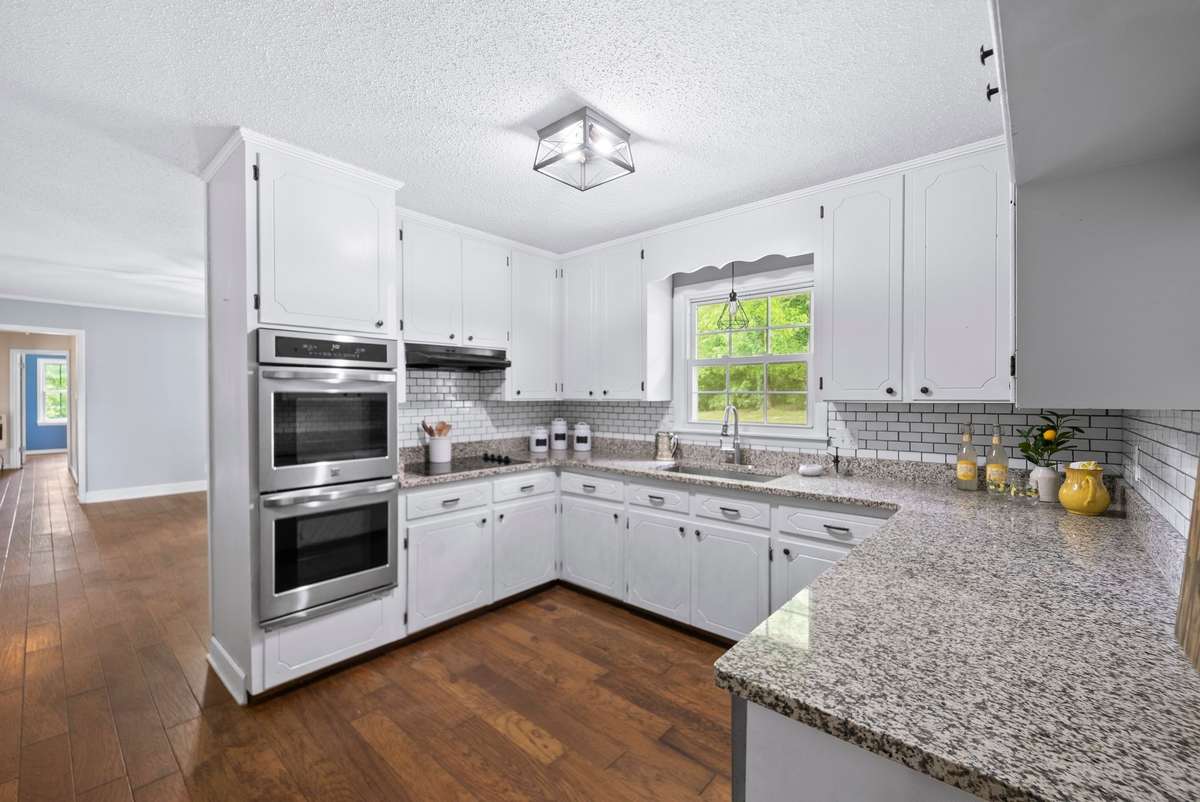 This kitchen has it all with granite countertops, subway tile, stainless steel appliances, including a double oven, and updated light fixtures throughout the home.